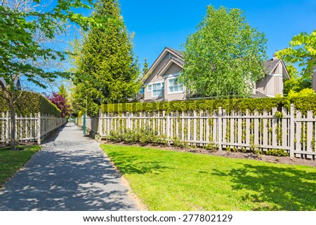 A perfect neighborhood on a sunny day with blue sky. Houses and townhouses with a green belt and wooden fence in suburbs at Spring in the north America.