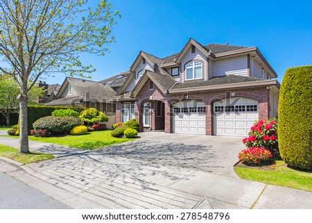 Luxury house with nicely trimmed and designed front yard, lawn in a residential neighbourhood in Canada.