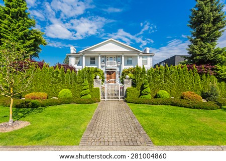 Custom built luxury house with nicely trimmed front yard, lawn in a residential neighborhood in North America on a sunny day.