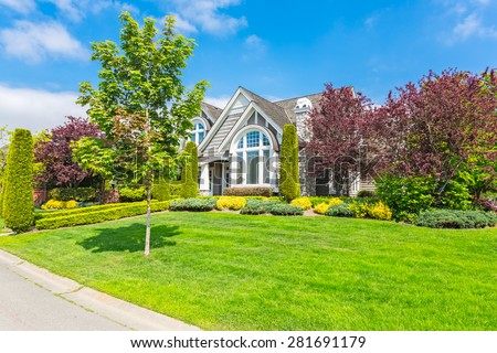 Custom built luxury house with nicely trimmed and designed front yard, lawn in a residential neighborhood in Canada.