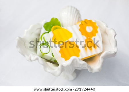 Hand made soap on white cloth in porcelain shell dish. Isolated, white background. Bathroom hardware.