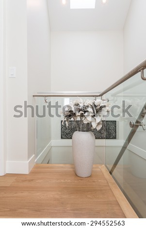 Stairs to the second floor in a luxury house with a flower vase, decoration. Interior design.