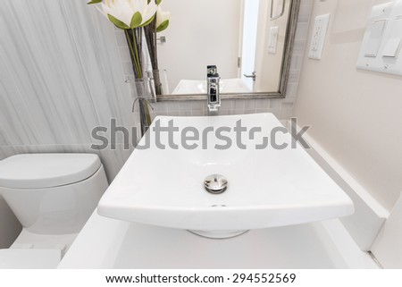 Fragment of a luxury bathroom with flowers and towels. View of a white modern sink. Interior design.