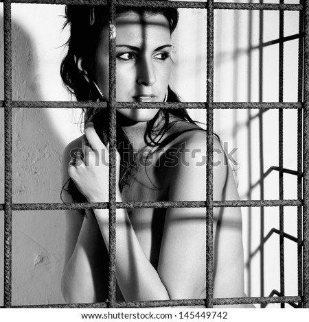 beautiful woman locked in a cage with black iron prison or jail bars