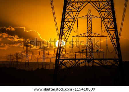 Sun setting behind the silhouette of electricity pylons