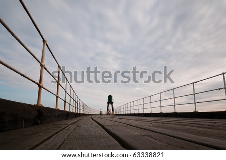 A worms eye view of an empty pier in the coastal town of Whitby, England. The harbor beacon can be seen at the end of the pier.