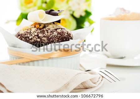 Chocolate muffin with white and dark chocolate on the top and flower as decoration in the background