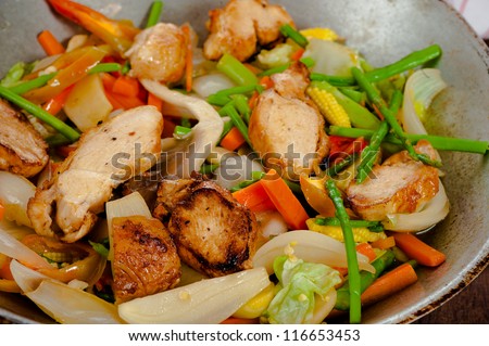 low fat asian vegetable dish with chicken in a wok on wooden table