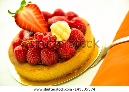 A small fruits tart with strawberry raspberry currant and a piece of chocolate on white background