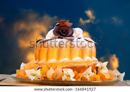 bundt cake on plate decorated with chocolate flowers and blue sky as background