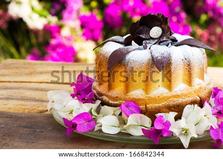 bundt cake on plate decorated with chocolate flowers and garden as background