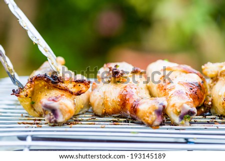 Three grilled chicken legs on a barbecue grill, outdoor in garden