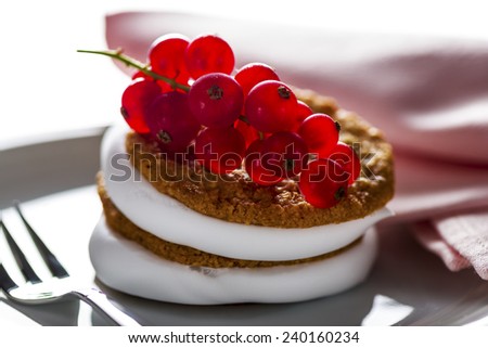 small cake with cream topping with currant on white plate