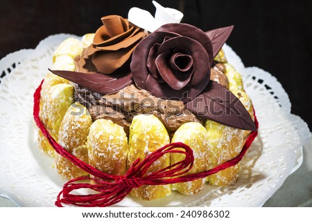 Beautifully decorated chocolate cake topped with roses on cocoa icing and surrounded with freshly baked golden pastries for a delicious dessert or sweet