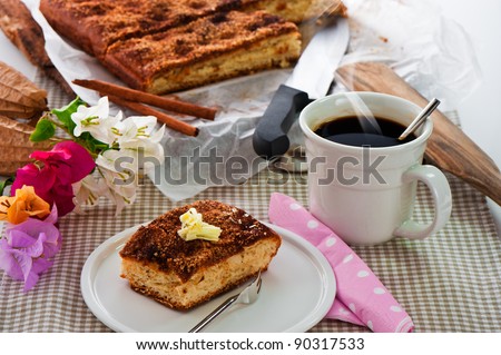 A sheet cake with cinnamon sugar butter and a hot cup of coffee