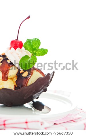 Vanilla ice with caramel, chocolate sauce, nuts and cherry in a bowl from chocolate on white background