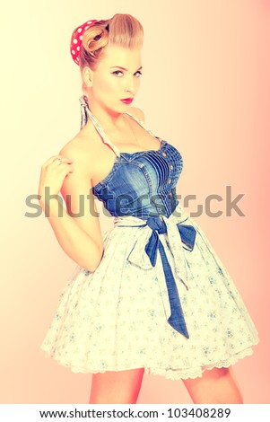 Beautiful young woman with pin-up make-up and hairstyle posing over pink background.