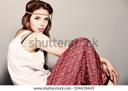 Romantic young woman in hippie style posing at studio.