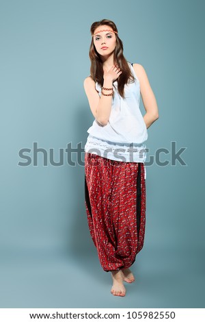 Romantic young woman in hippie style posing at studio.