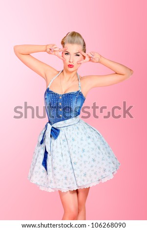 Beautiful young woman with pin-up make-up and hairstyle posing over pink background.