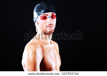 Portrait of a man professional  swimmer posing at studio over black background.