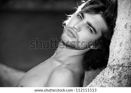 Black-white portrait of a handsome male model posing at the seaside.