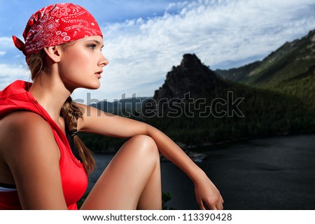 Young woman tourist is looking into the distance at the top of a mountain.