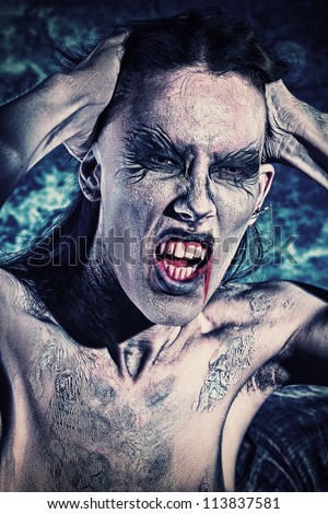 Portrait of a screaming vampire at the night background. Halloween.