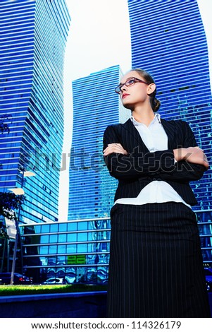 Young business woman standing in the big city and purposefully looking away.