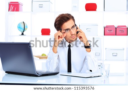 Handsome businessman is calling on his cell phone at the office.