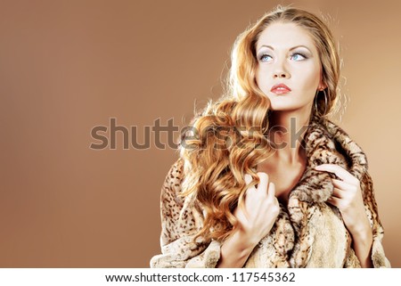 Beautiful glamorous woman in fur coat posing at studio.