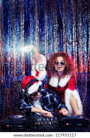 DJ man mixing up some Christmas cheer with attractive snow maiden. Disco lights in the background.