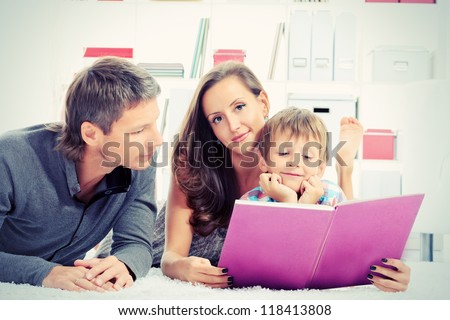 Portrait of a happy parents reading a book with their son.