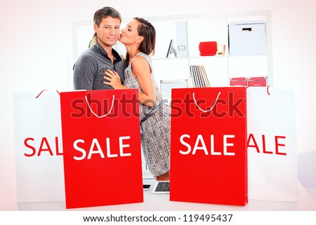 Seasonal sale: happy couple holding shopping bags inside of a store.