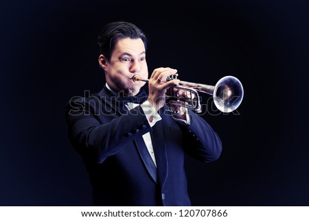 Portrait of a musician playing the trumpet. Black background.