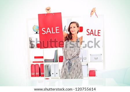 Seasonal sale: happy young woman holding shopping bags inside of a store.