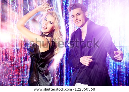 Couple of cheerful young people dancing at a party.