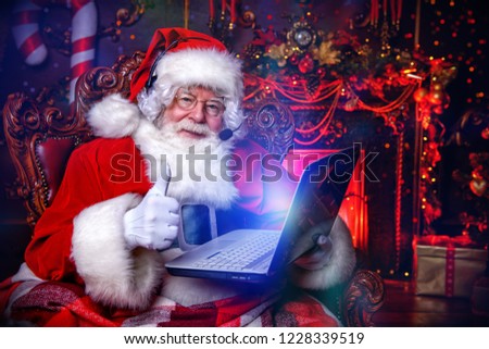 A portrait of Santa Claus sitting at his home with a laptop. Miracle time. Christmas, New Year.