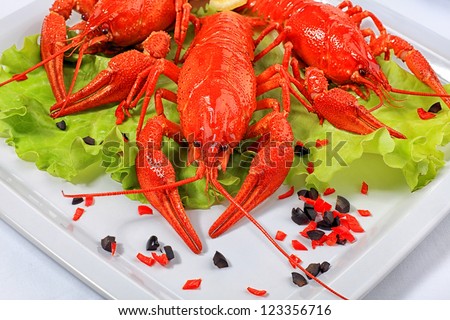 A dish with boiled crawfish, lemon and lettuce.