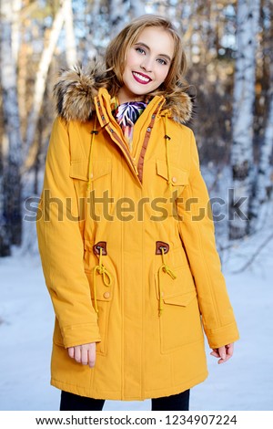Girl walking in forest on winter day. Fashion shot. Down Jackets.