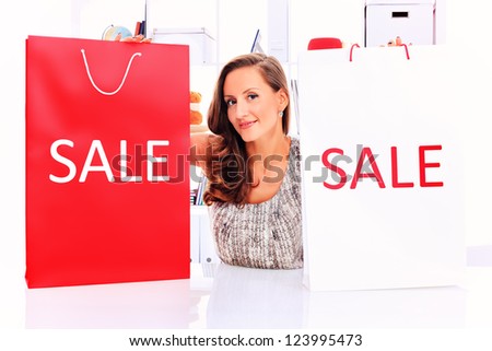 Seasonal sale: happy young woman holding shopping bags inside of a store.