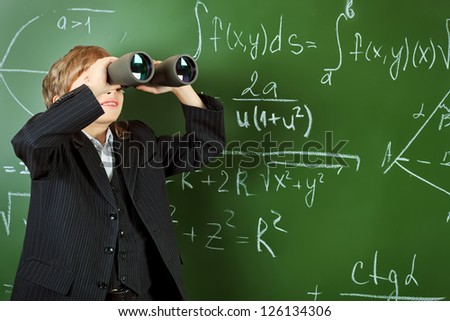 Schoolboy looking through the binoculars at a classroom.