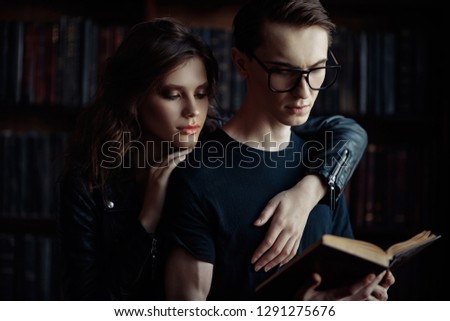 Portrait of an attractive young people in love read a book in the library. Beauty, fashion.