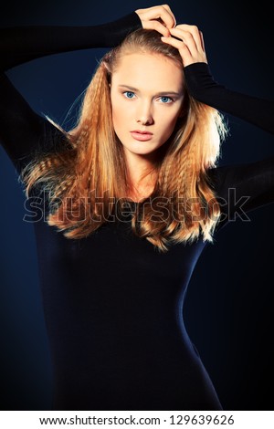 Portrait of a beautiful young woman in black blouse over dark background.