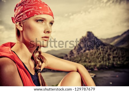 Young woman tourist is looking into the distance at the top of a mountain.