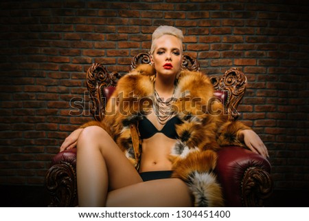 Portrait of a beautiful woman in luxurious fur coat posing in interior. Luxury, rich lifestyle. Fashion shot.