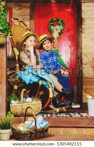 Easter holidays. Happy children are posing on the porch of a village house. Easter decorations.