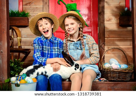 Easter holidays. Happy children are posing on the porch of a village house. Easter decorations.