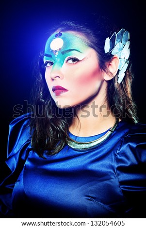 Portrait of a beautiful young woman with fantasy makeup. Black background.