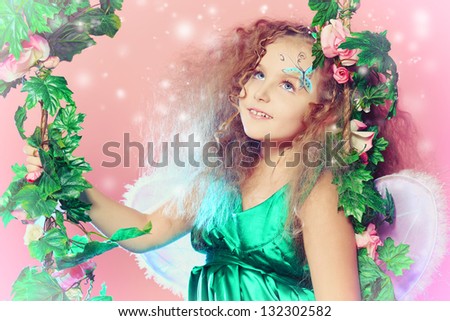 Beautiful little fairy swinging on a swing over pink background.